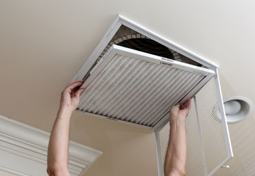 Person changing air filter on the ceiling