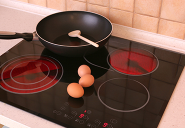 Electric stove top with skillet, eggs and wooden spoon