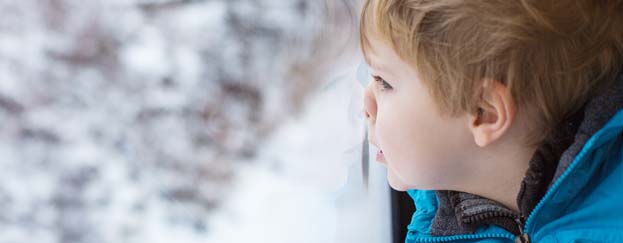 Child looking out window at snowy ground