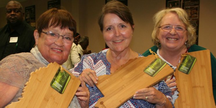 Three members at annual meeting holding Mississippi cutting boards