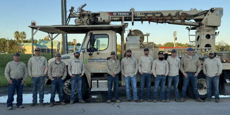 Linemen stand in front of a company truck